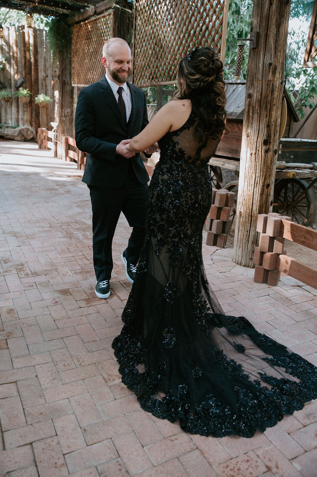 Couple holding hands during their first look beneath a rustic garden walkway at boojum tree hidden gardens.

