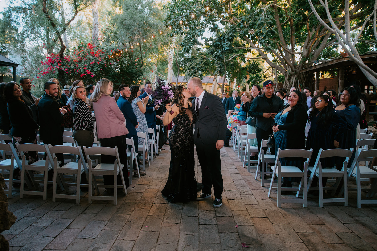 Bride and groom walking back down the aisle after their ceremony while guests cheer and celebrate.
