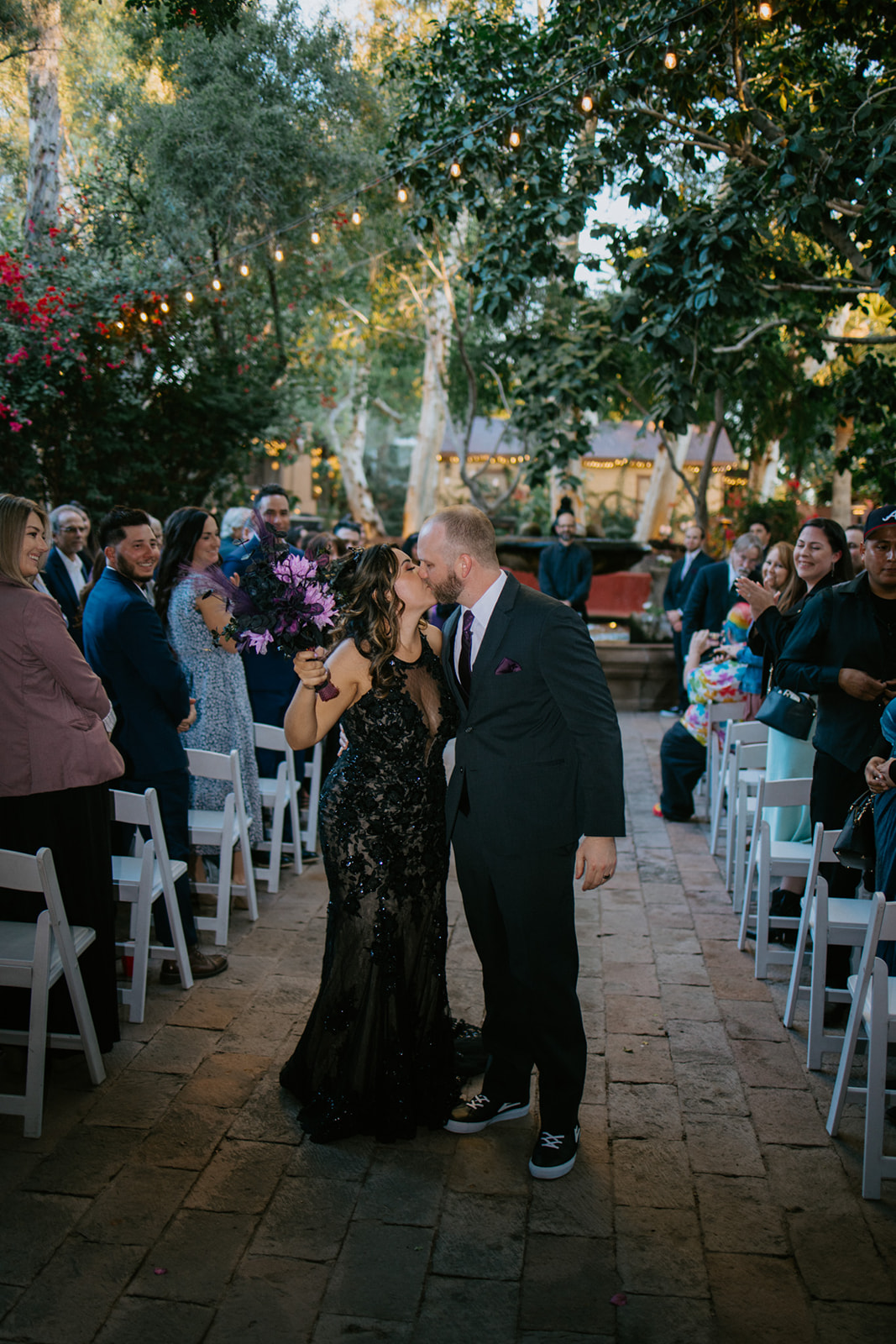 Newlyweds kissing as they walk back down the aisle after their boojum tree hidden gardens wedding ceremony.
