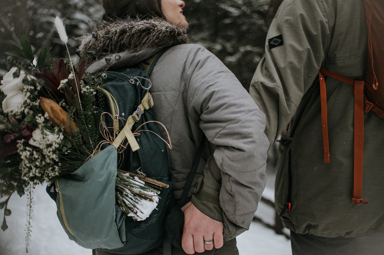 Close-up of bridal bouquet secured to a backpack during a snowy mountain elopement hike