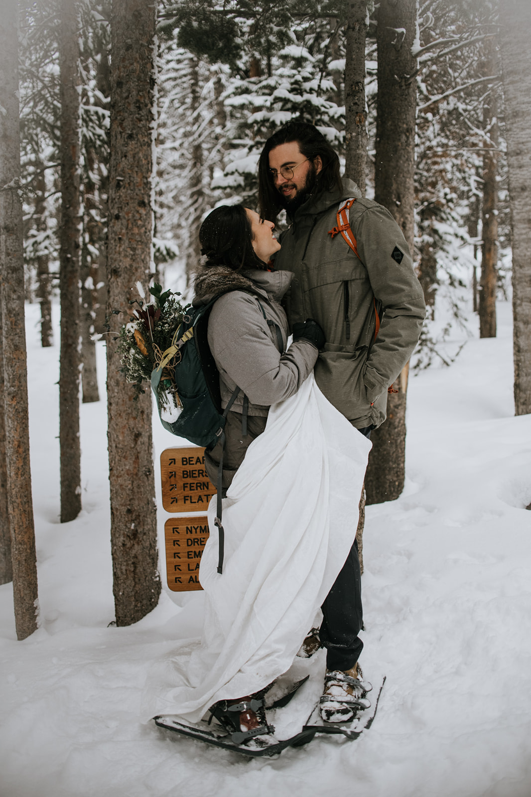 Couple standing together in deep snow during a winter mountain elopement surrounded by pine trees