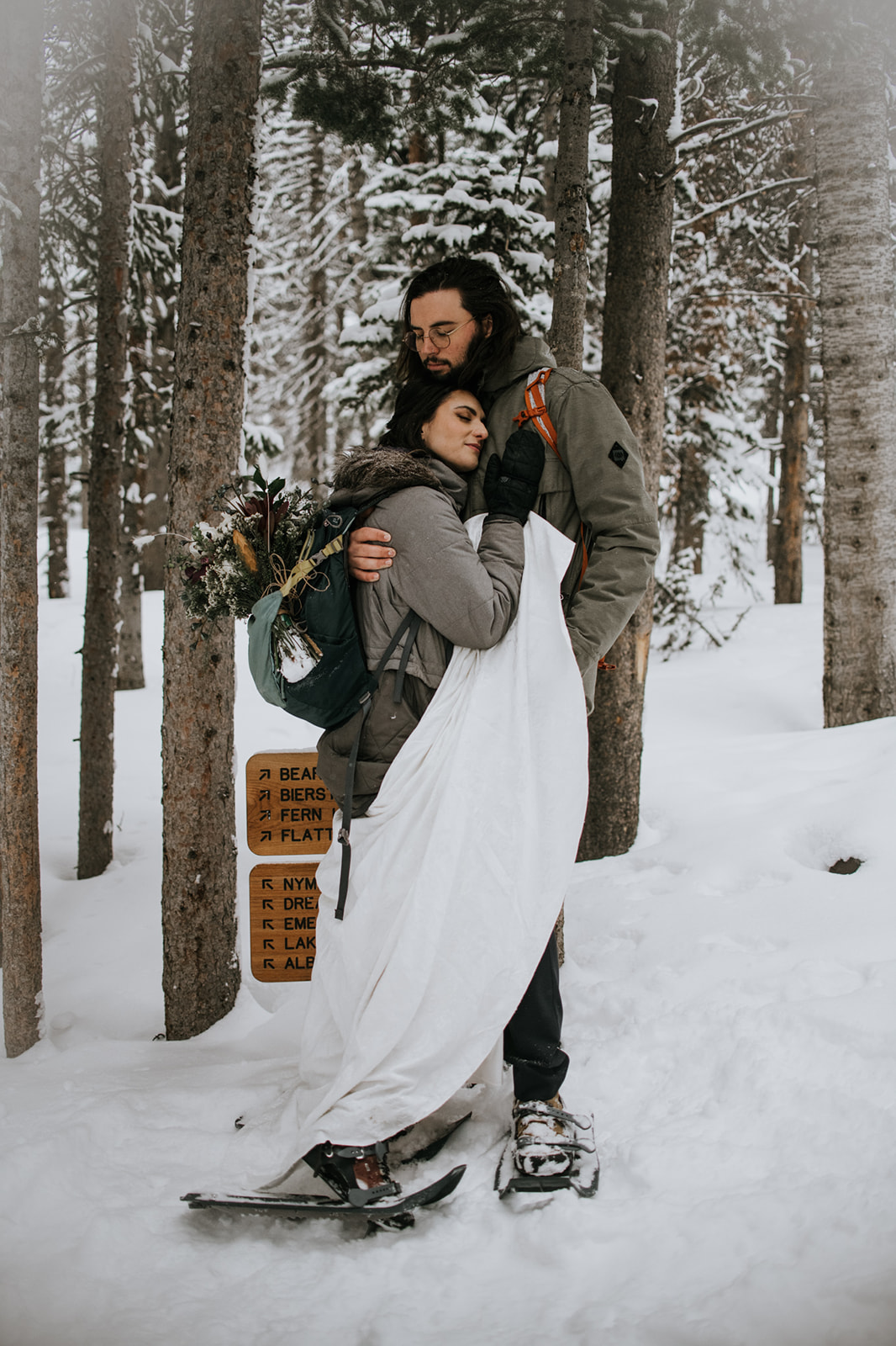 Bride and groom embracing in falling snow during an intimate winter elopement in the mountains
