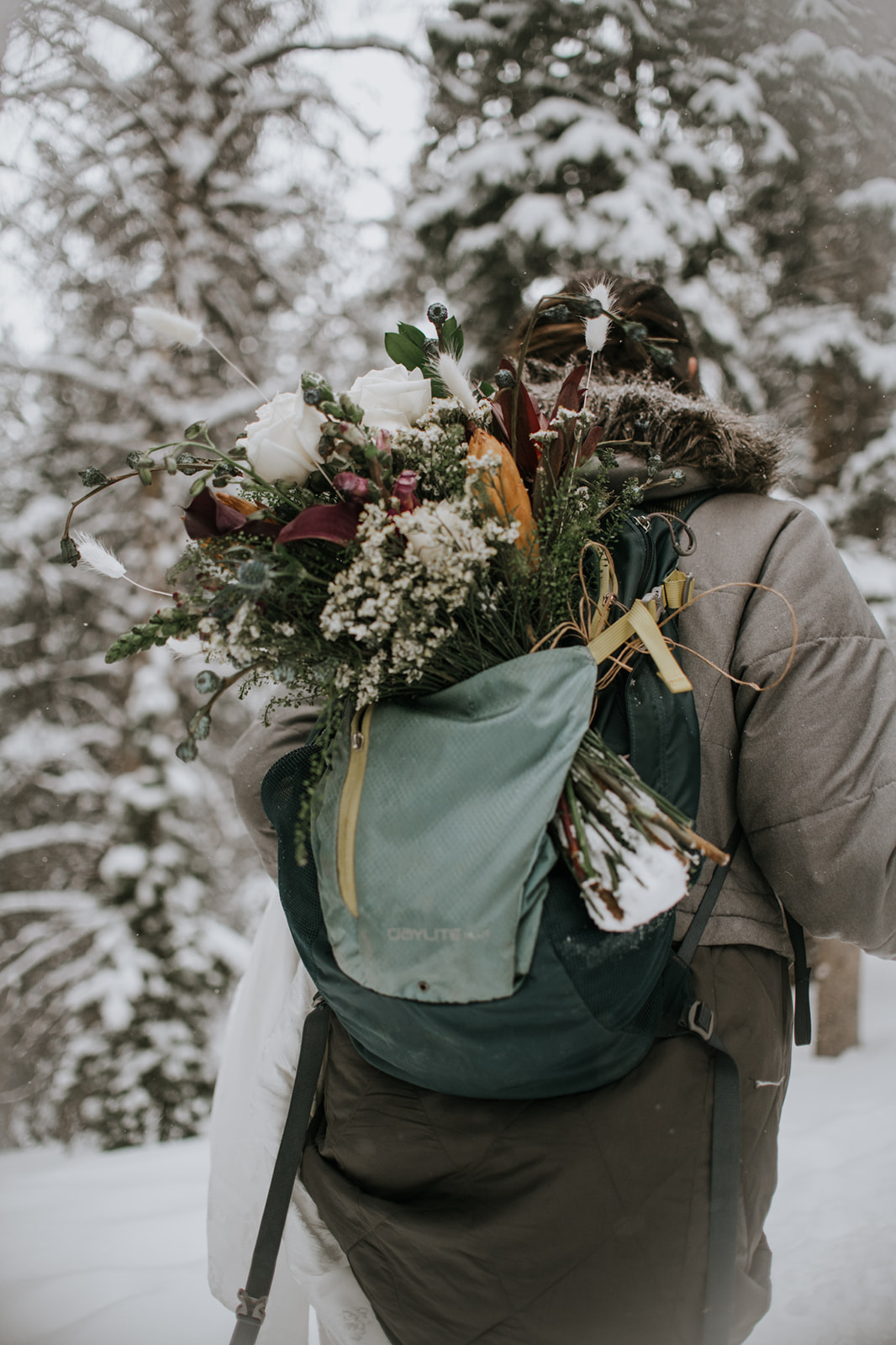 Wide snowy landscape with couple walking together during a rocky mountain national park elopement in a snowstorm