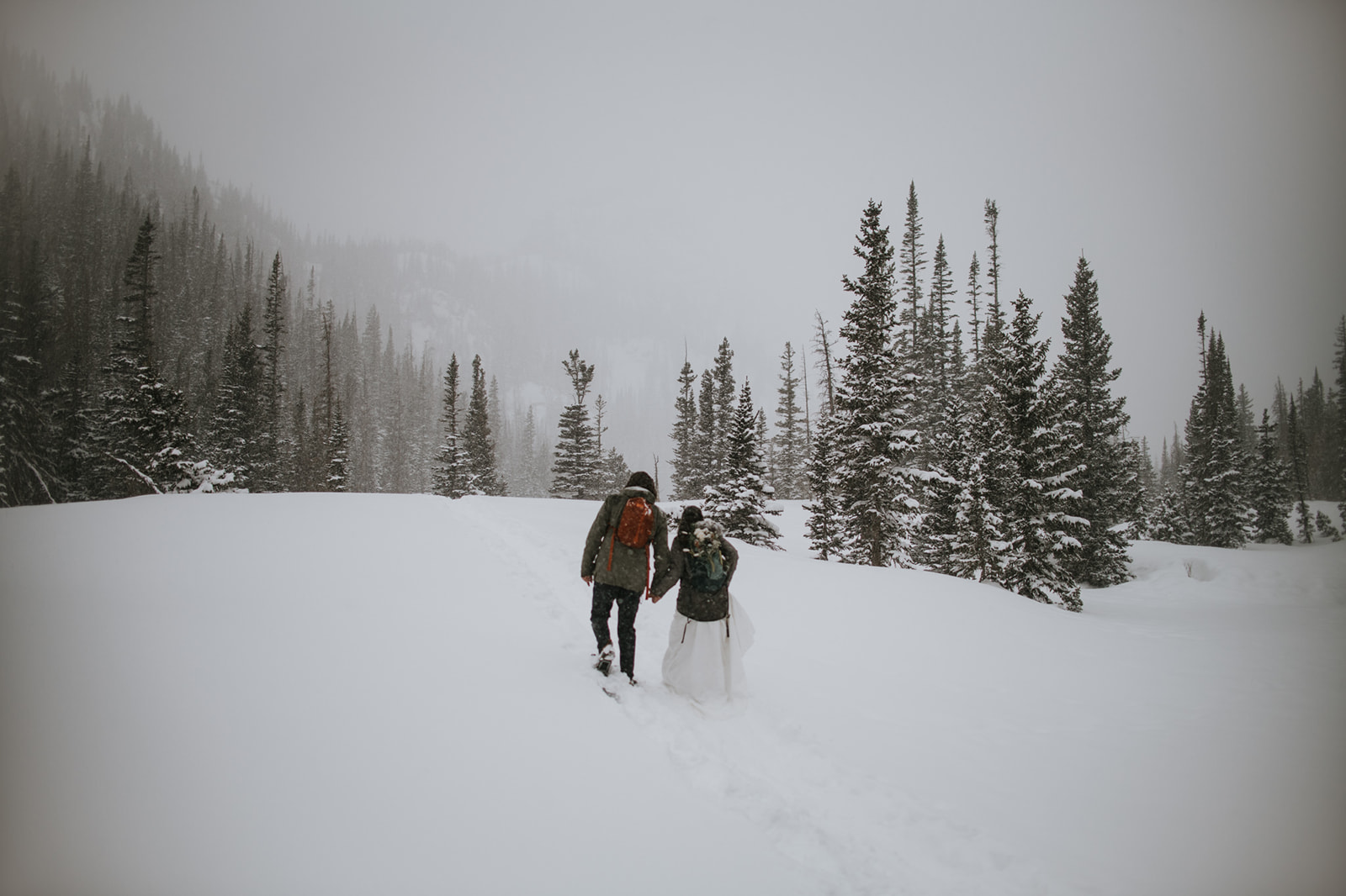 Bridal bouquet carried in a backpack during a rocky mountain national park elopement in snowy conditions