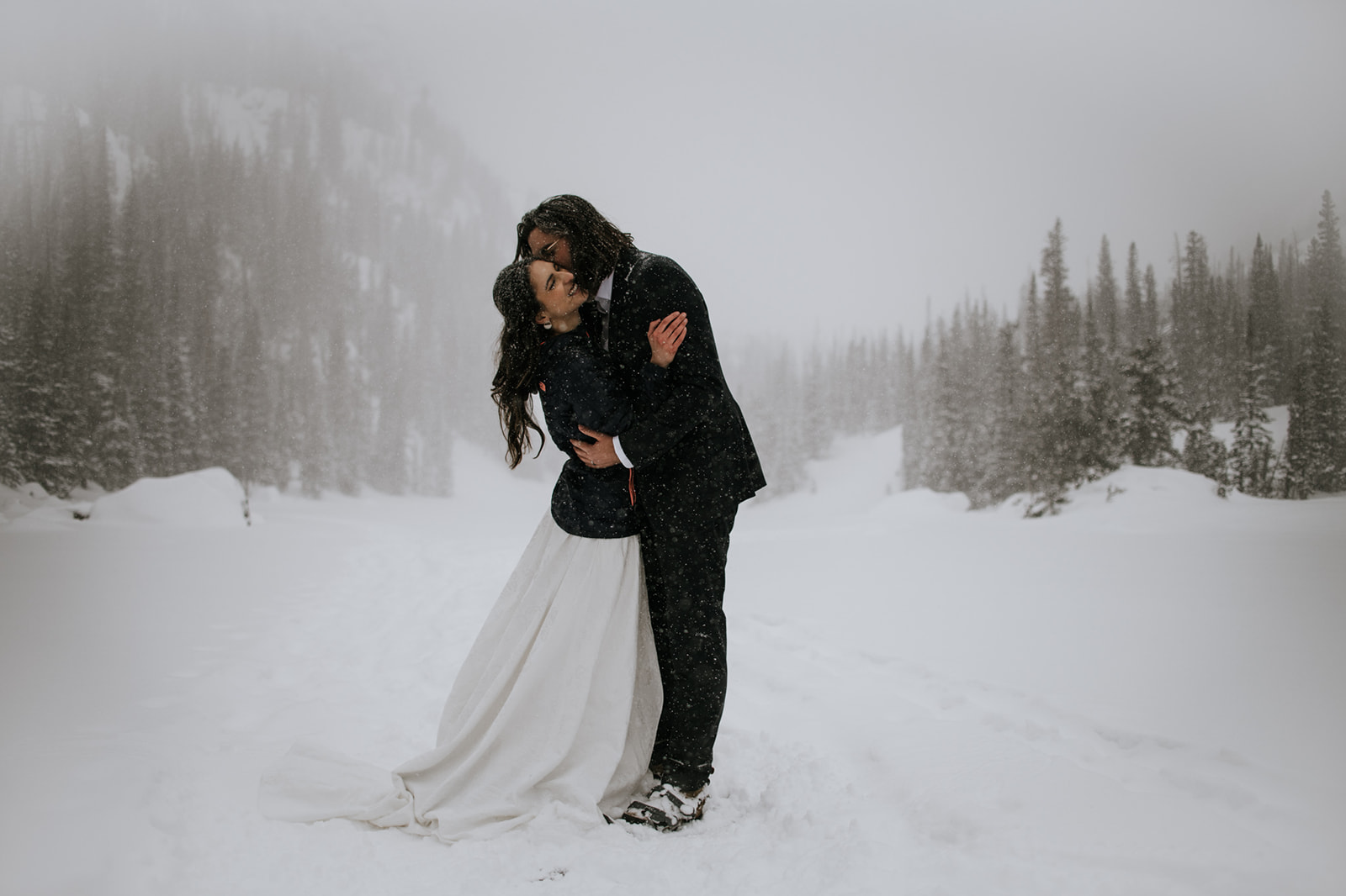 Bride and groom kissing in a snowstorm during an intimate winter elopement in the mountains