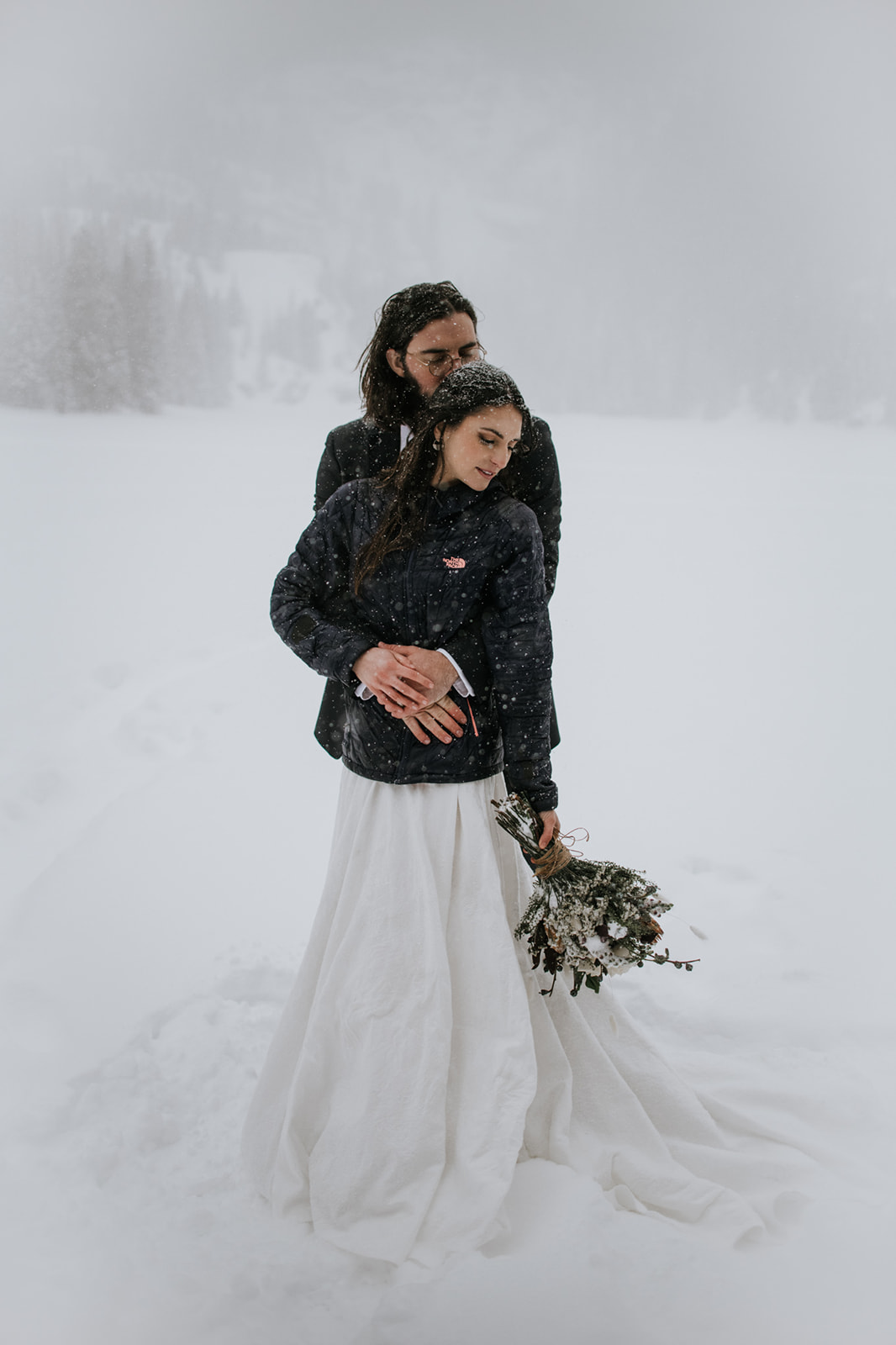Bride and groom embracing in a snowstorm during a rocky mountain national park elopement