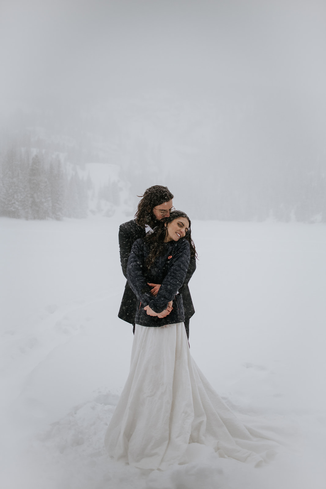 Couple embracing quietly in deep snow during a rocky mountain national park elopement in winter