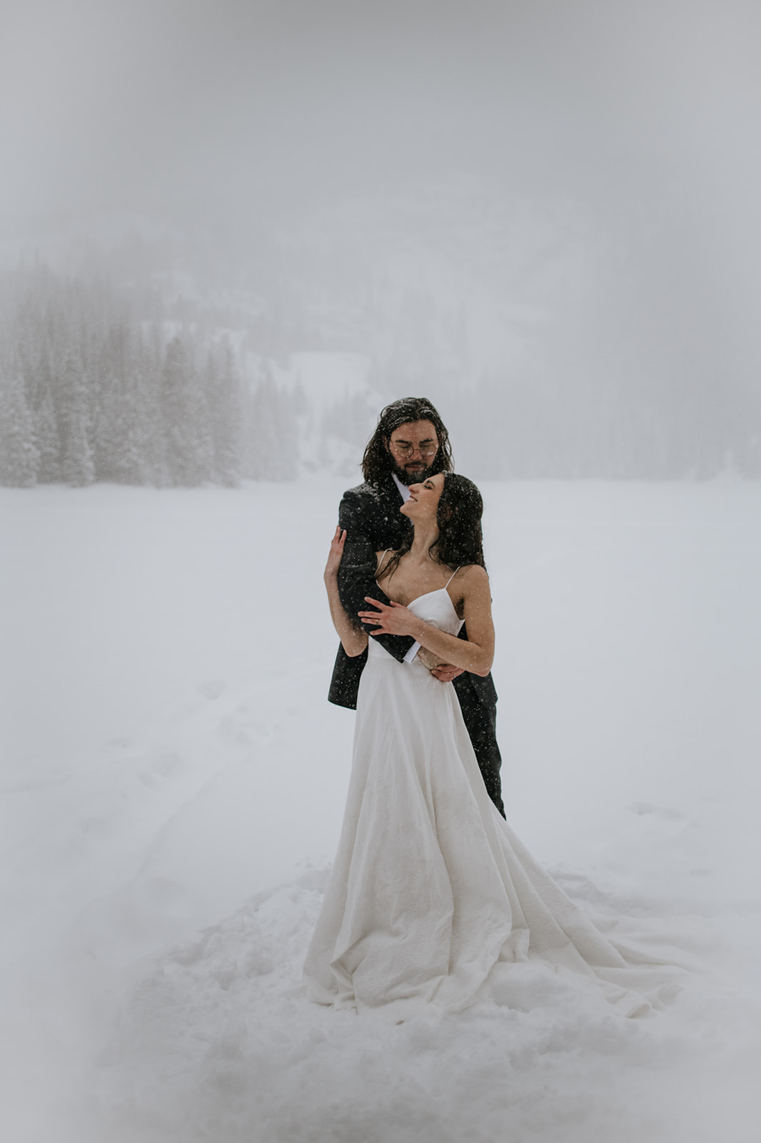 Bride and groom holding each other close on a frozen lake during a rocky mountain national park elopement
