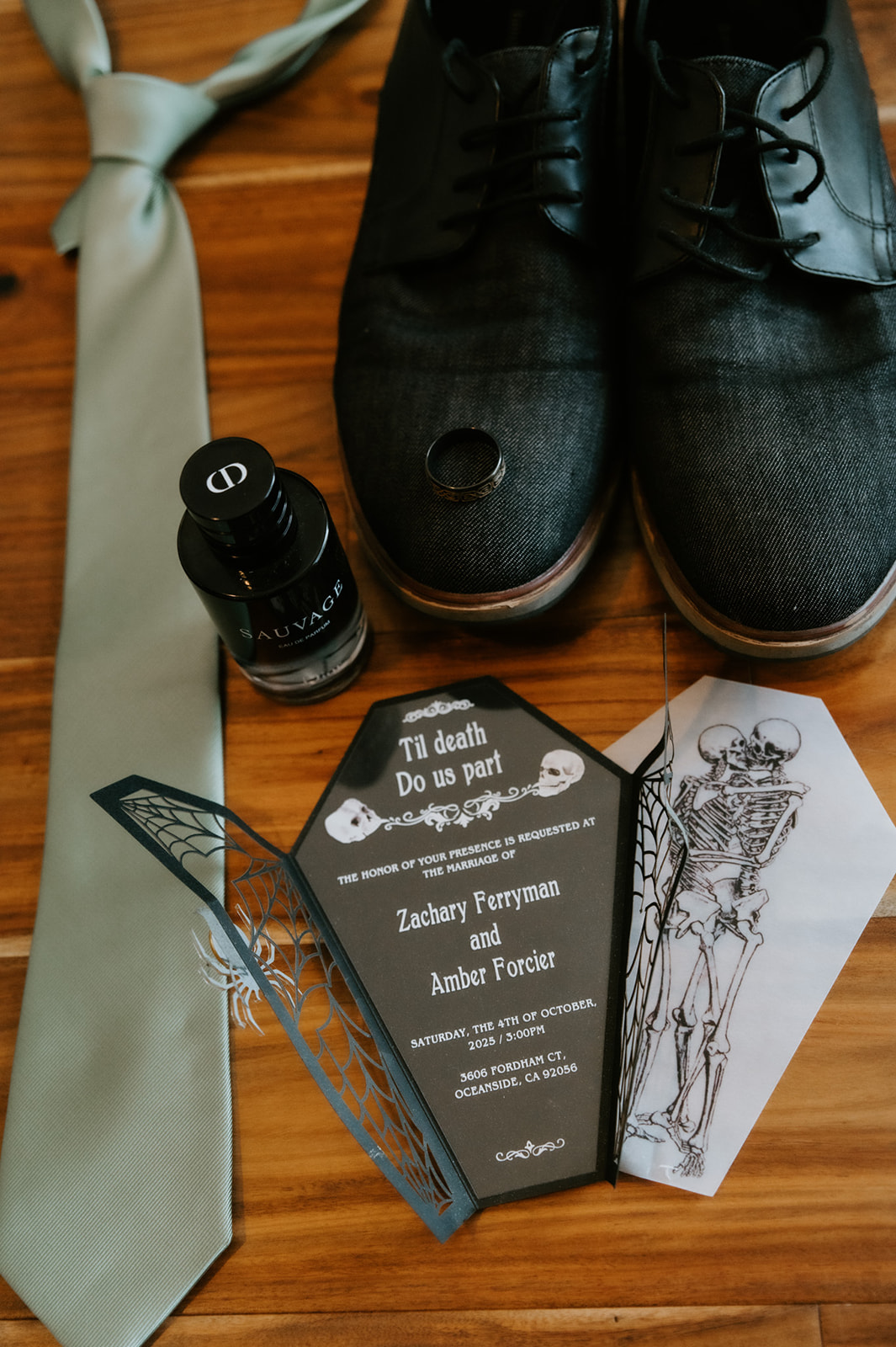 Groom’s shoes, tie, cologne, and coffin-shaped wedding invitation laid out for an Airbnb wedding during a California elopement.