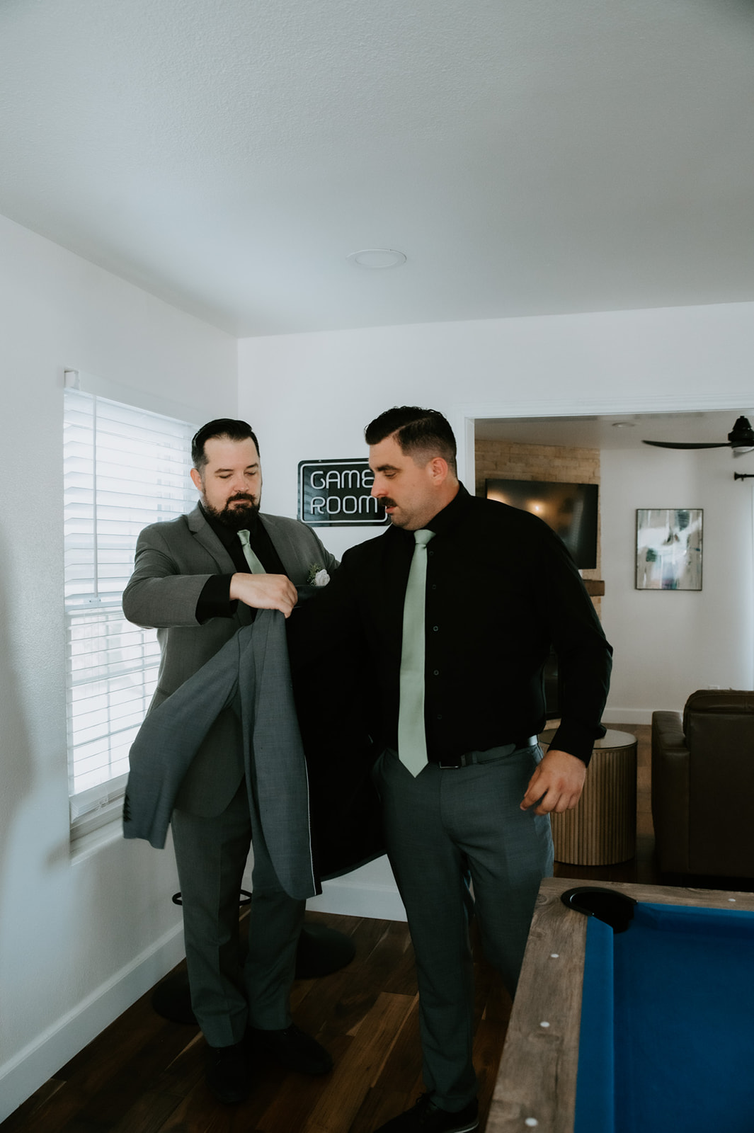 Groom’s jacket being helped on by a groomsman, capturing a supportive, behind-the-scenes moment when eloping with family.