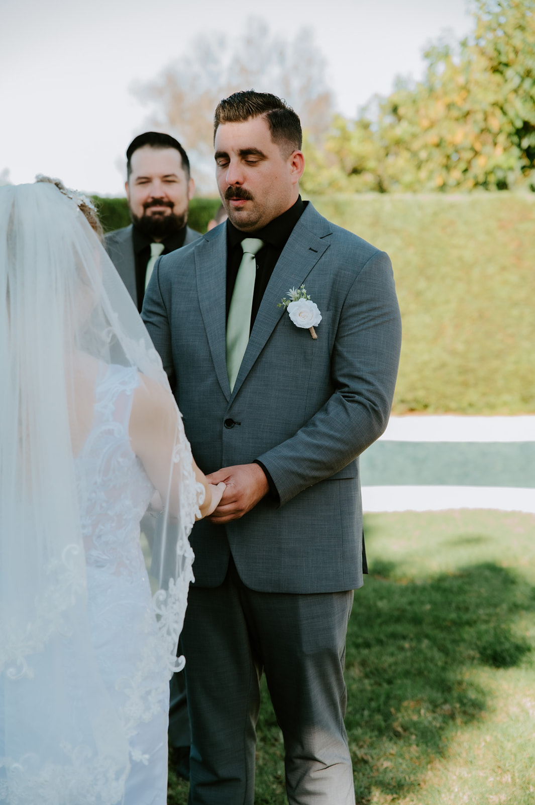 Groom holding the bride’s hands during an intimate outdoor ceremony, a quiet emotional moment while eloping with family in California.