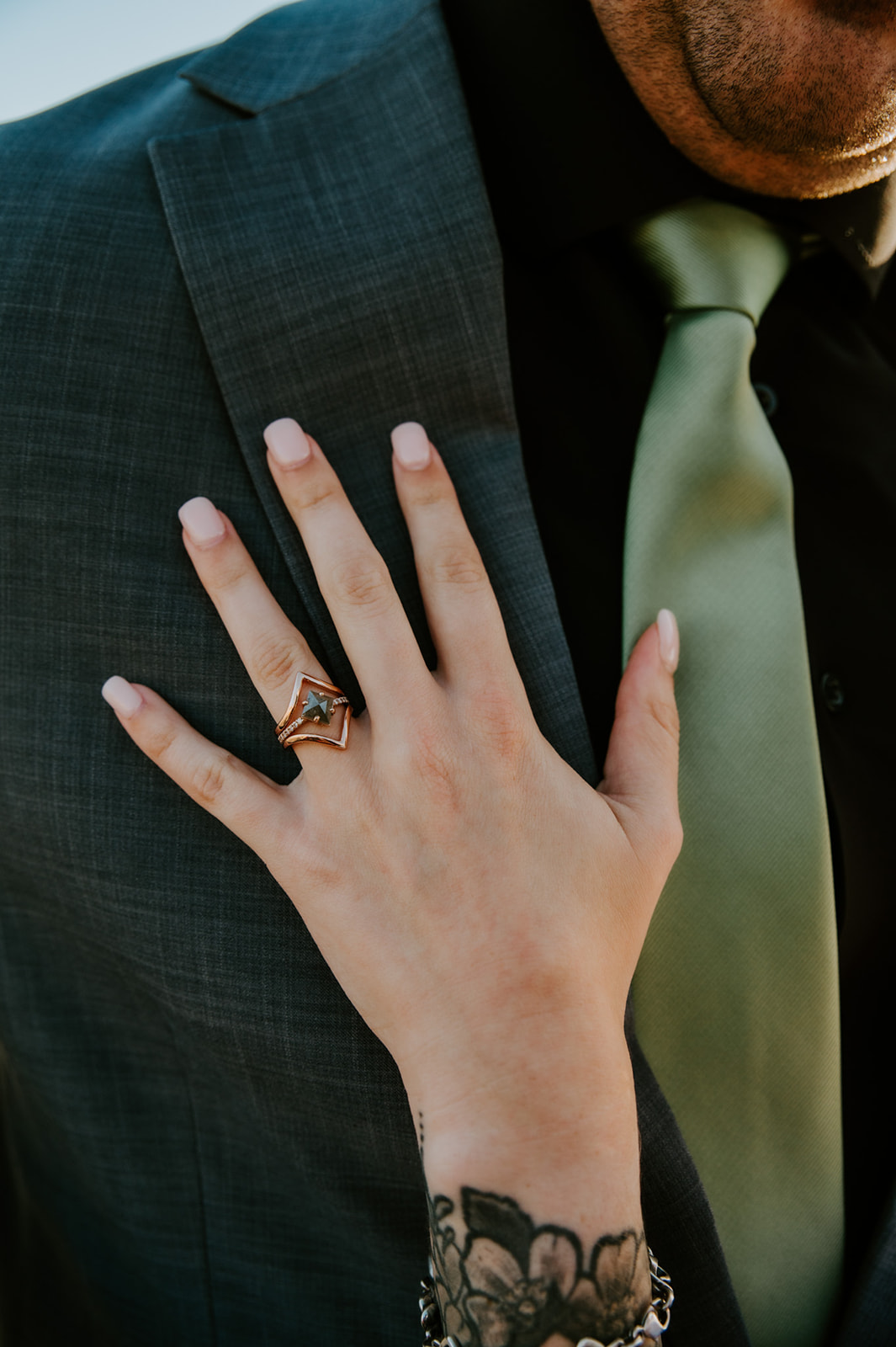 Close-up of the bride’s engagement ring resting on the groom’s suit jacket during beach elopement photos after a family ceremony.