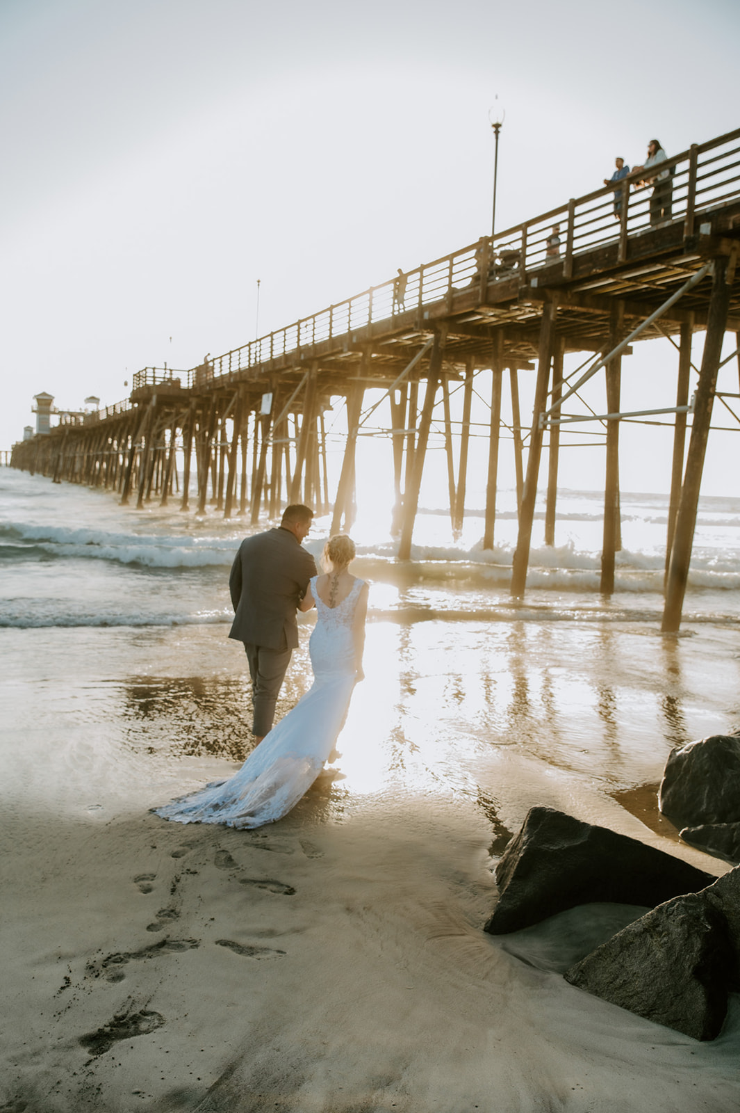 Bride and groom walking away together along the shoreline after their ceremony, a calm ending to a family-inclusive elopement day.