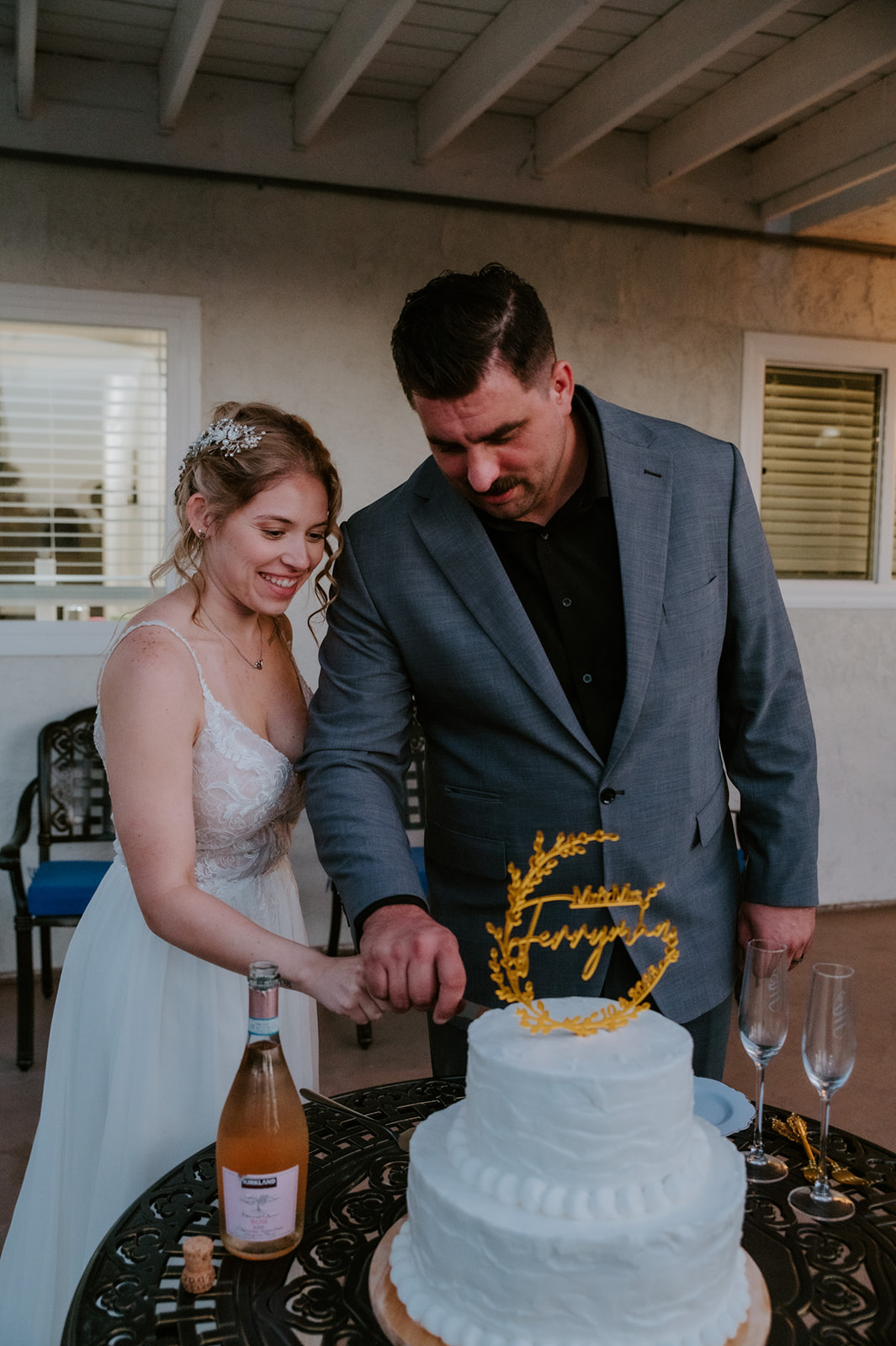 Bride and groom cutting into simple two tiered wedding cake after intimate elopement with family.