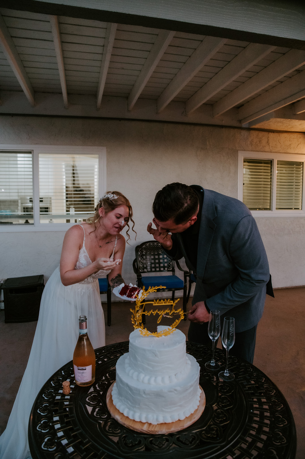 Bride playfully feeding the groom cake during an intimate Airbnb wedding celebration with family.