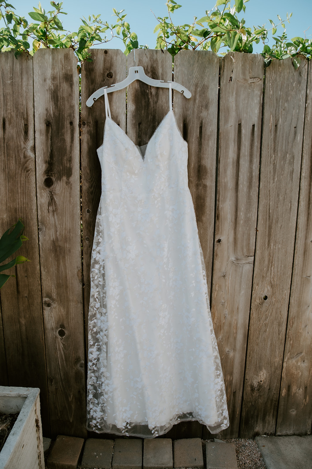 Wedding dress hanging on fence before intimate beach elopement in California. 