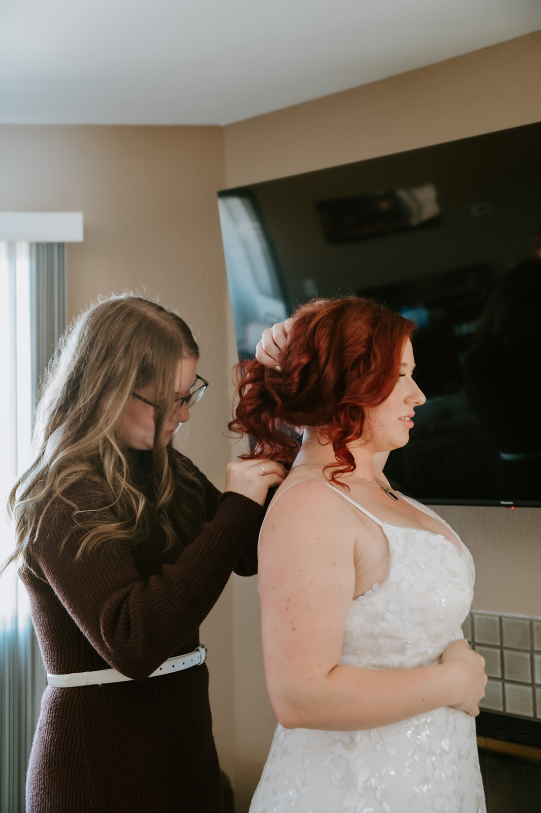 Bride's family helps her get ready by putting a necklace on. 
