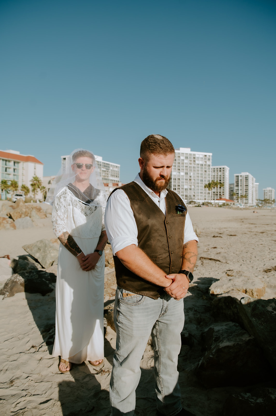 Groom's friend wearing wedding dress standing behind groom in a surprise first look. 