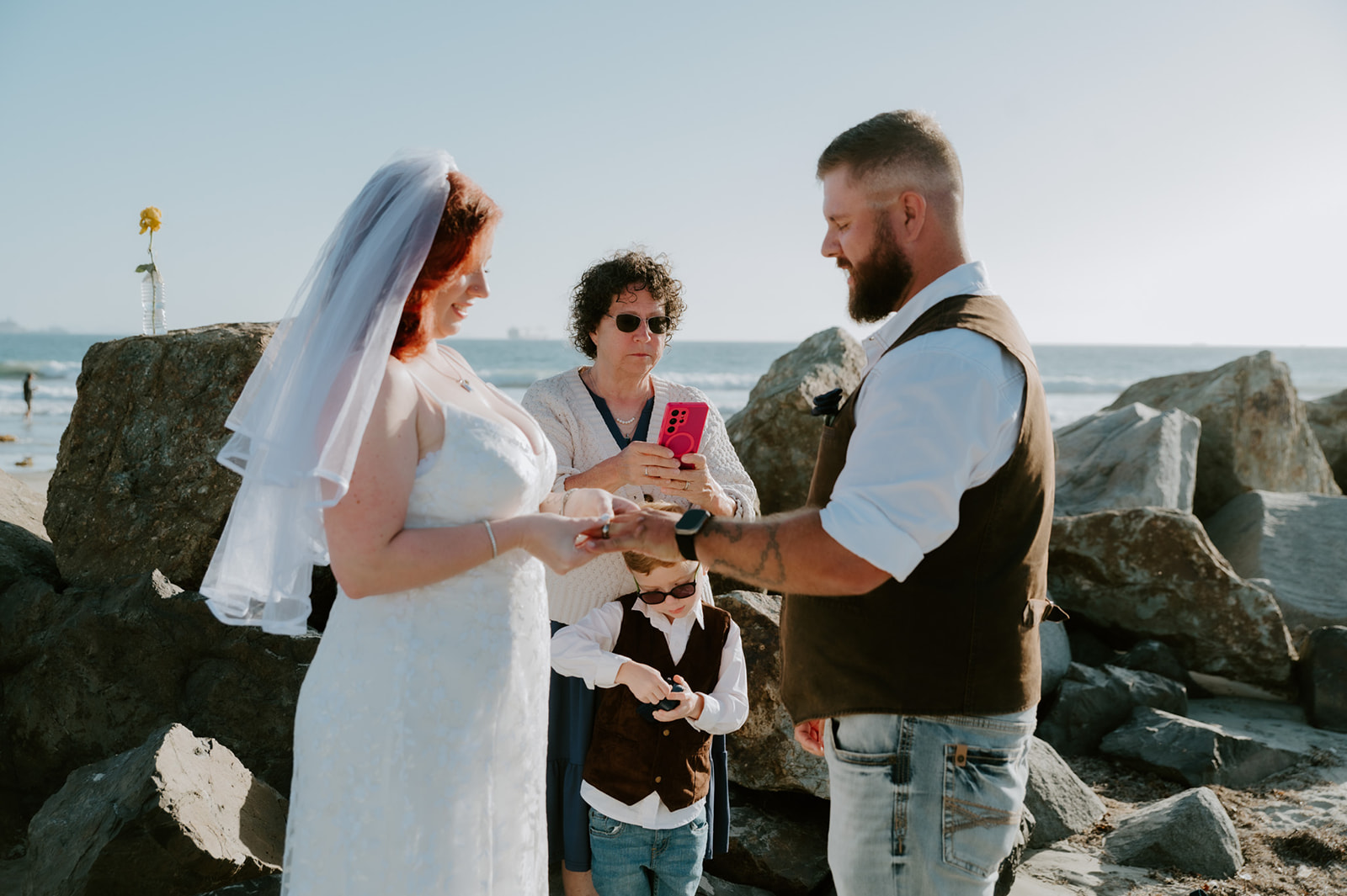 Bride placing ring on groom's finger during beach elopement ceremony in California, intimate moment captured by California elopement photographer. 