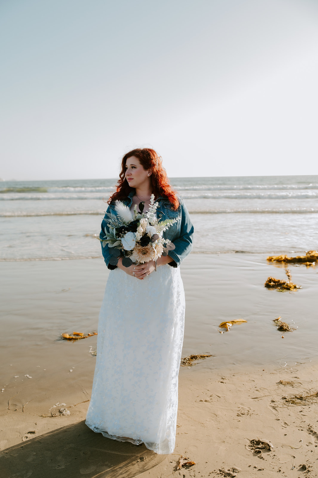 Bride standing alone on the beach holding a bouquet during a relaxed coastal elopement, captured by a California elopement photographer