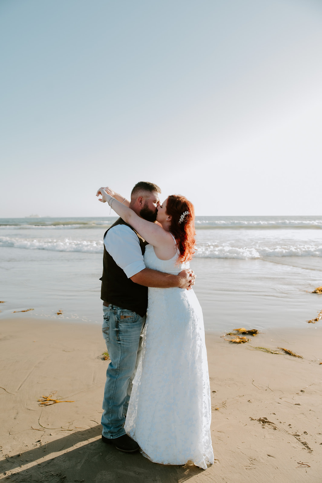 Bride and groom sharing a kiss with the ocean behind them during a simple California beach elopement.