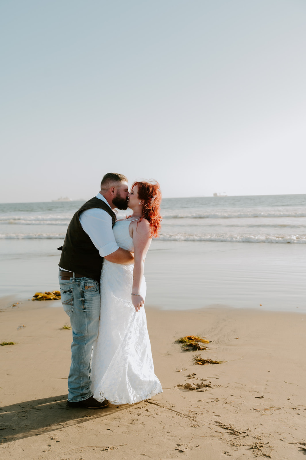 Couple sharing a quiet kiss on the shoreline during a simple beach elopement ceremony