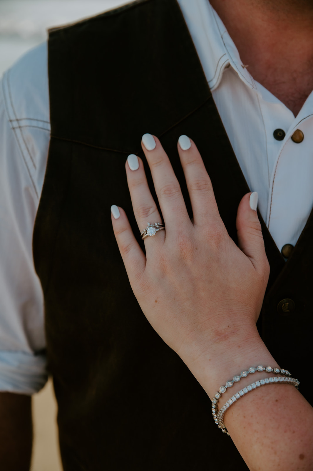 Bride placing hand with wedding ring on groom's chest to showcase her beautiful engagement ring and wedding band, captured by California elopement photographer. 