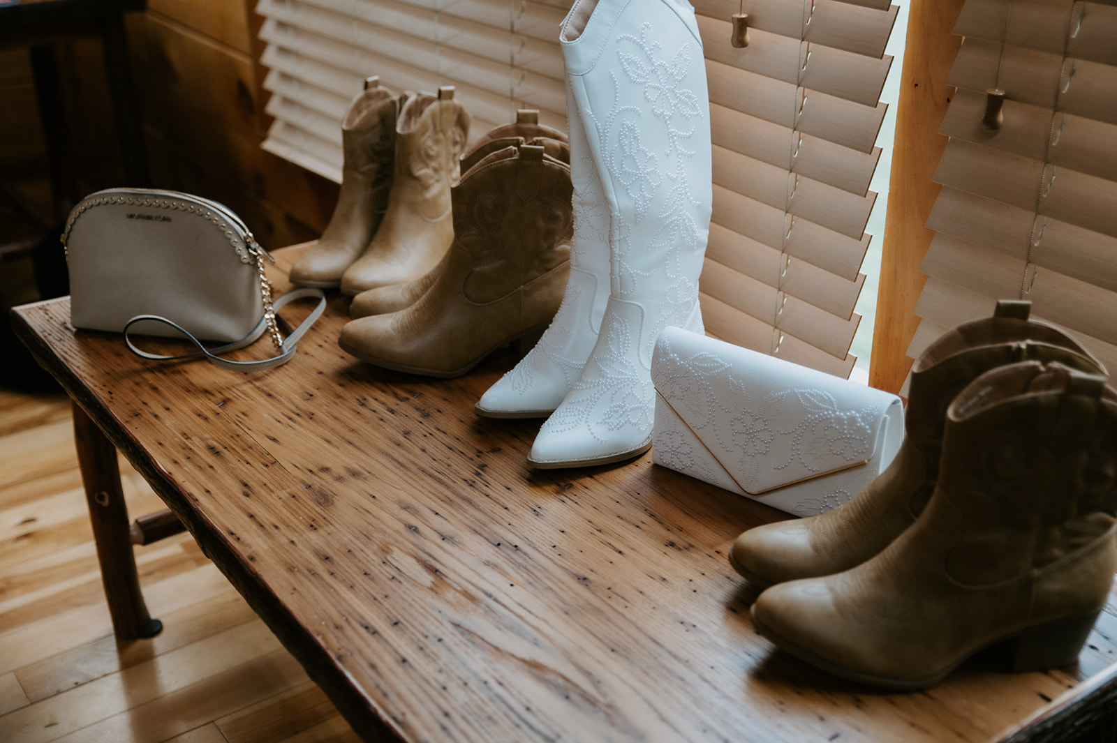 Bride’s boots, purse, and accessories laid out on a wooden bench inside the cabin.