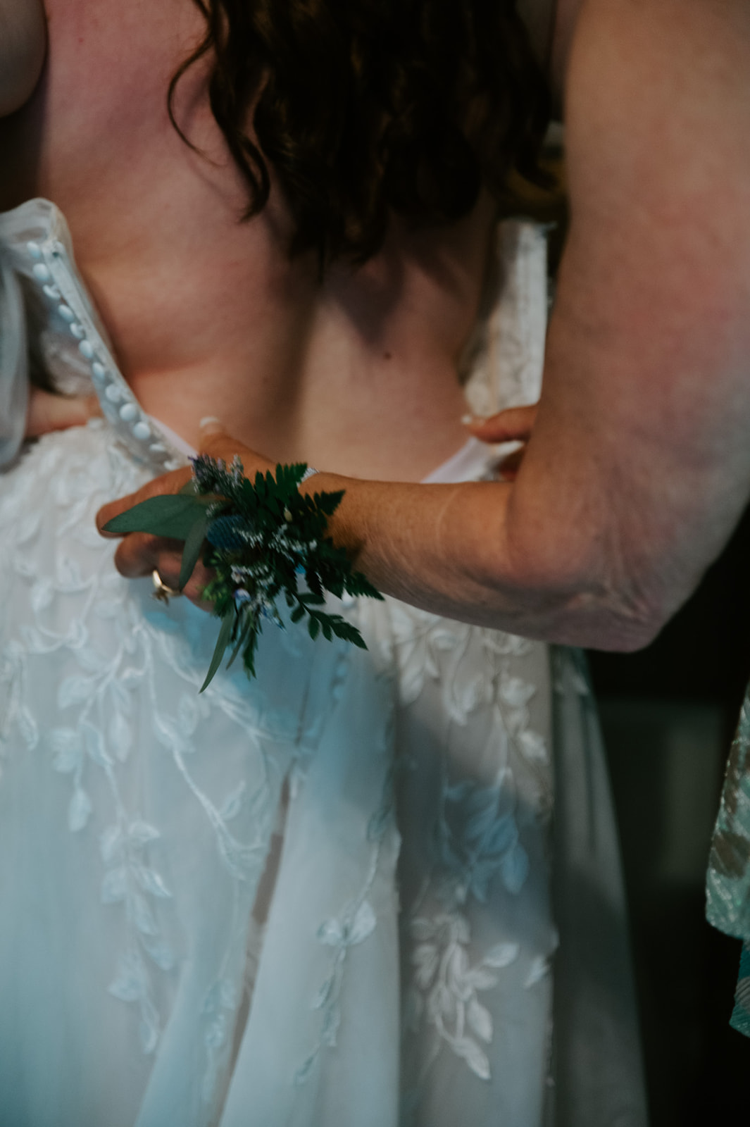 Close-up of hands adjusting the back of the bride’s dress before the ceremony.