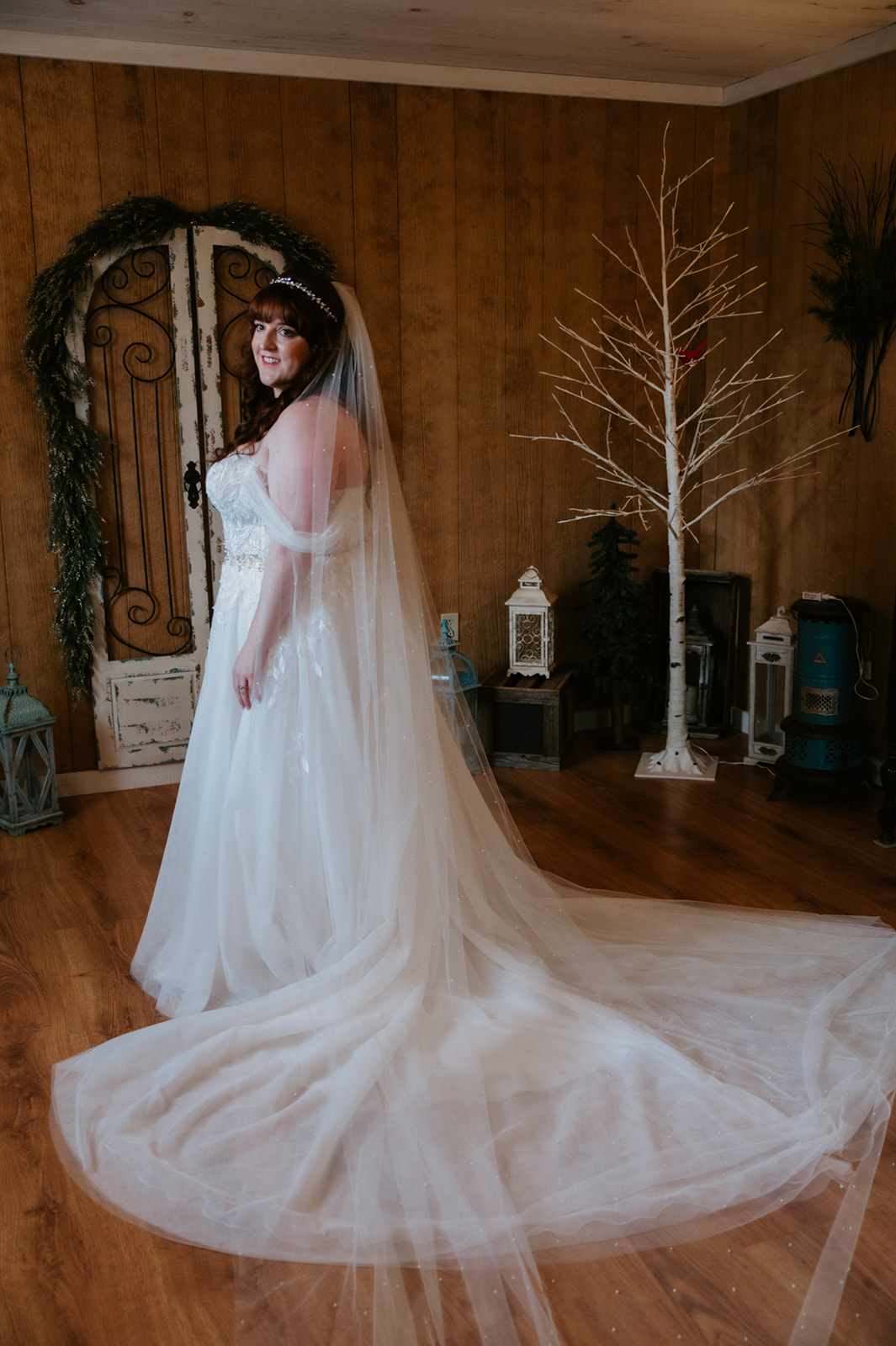 Bride standing indoors with her veil flowing behind her during pre-ceremony portraits.