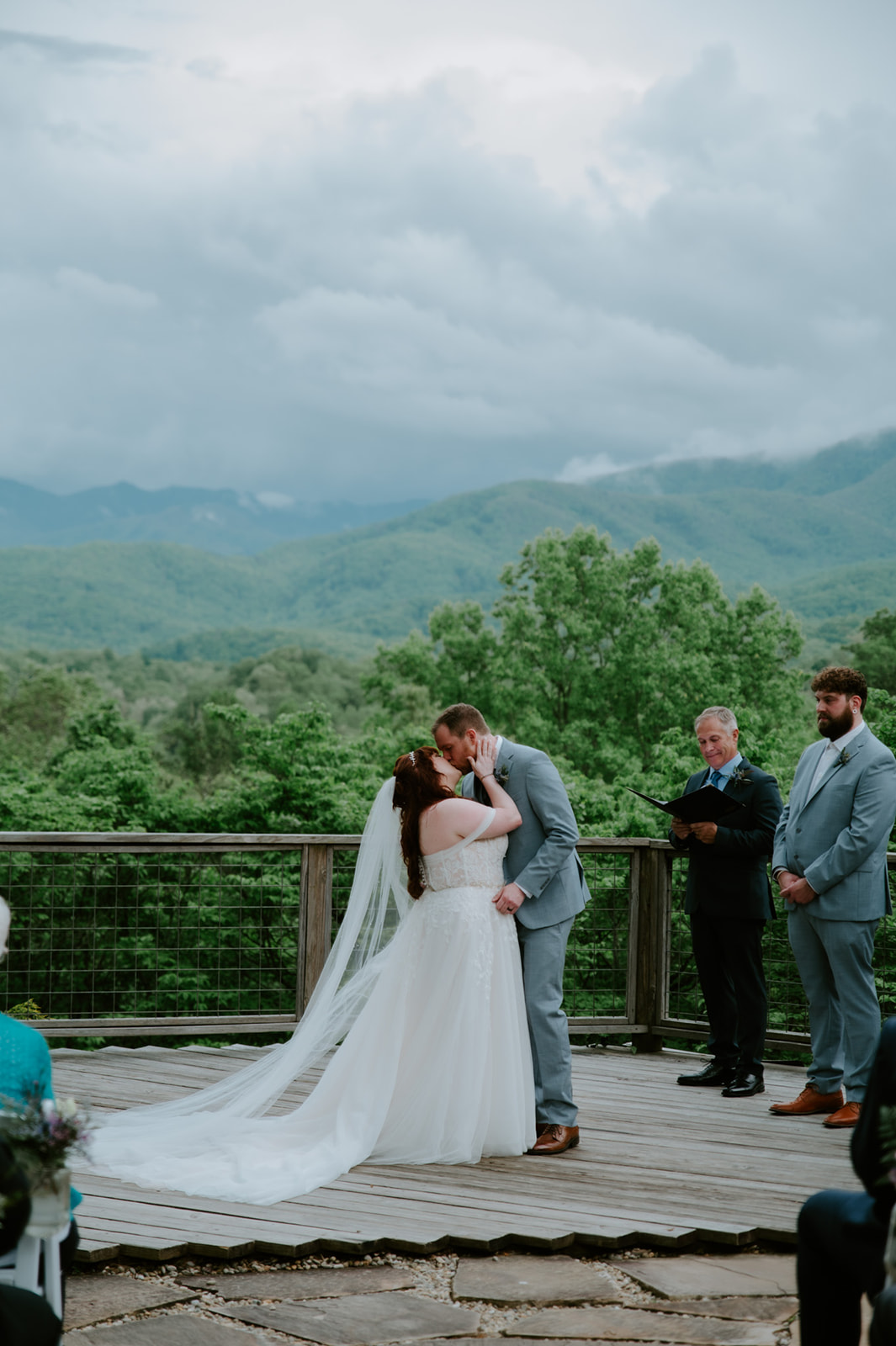 First kiss as newlyweds on a wooden ceremony deck overlooking the Smoky Mountains.