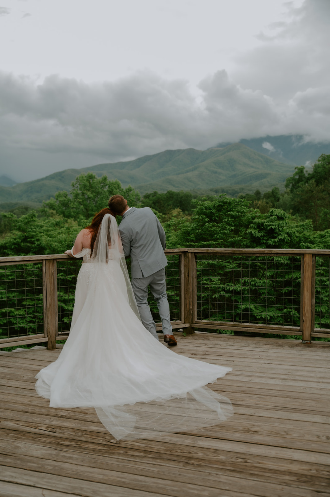 Bride and groom standing together on a wooden deck overlooking the Smoky Mountains after their ceremony