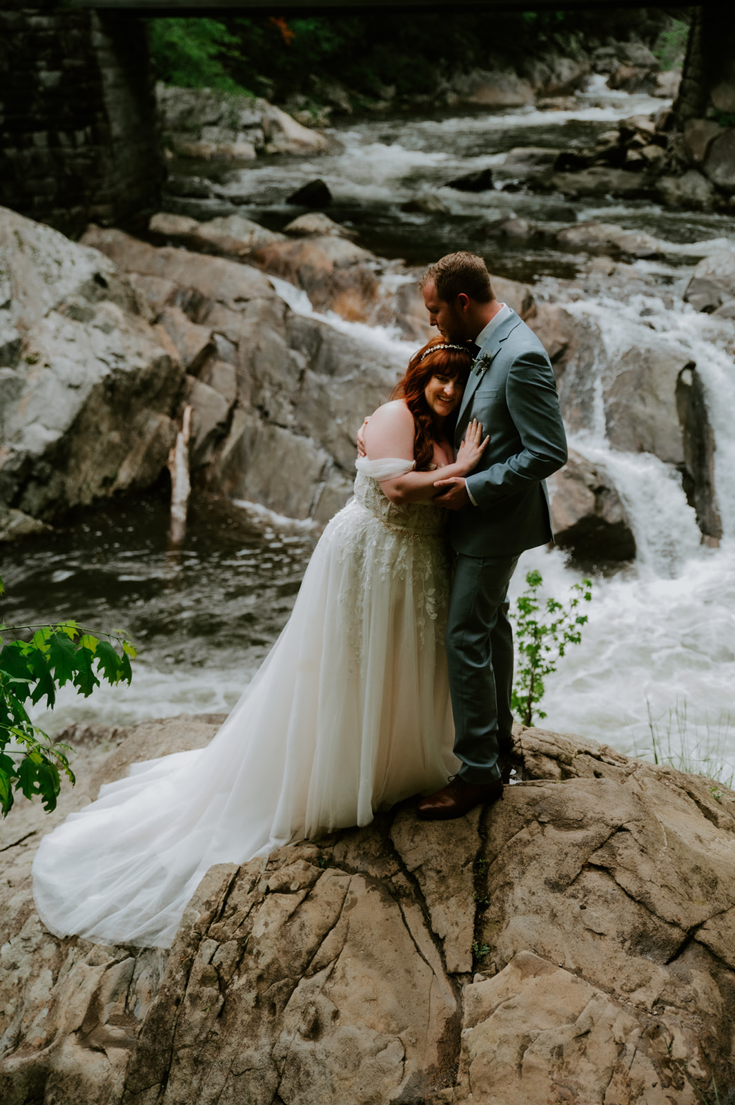 Bride and groom standing together in a foggy river as the water flows around them