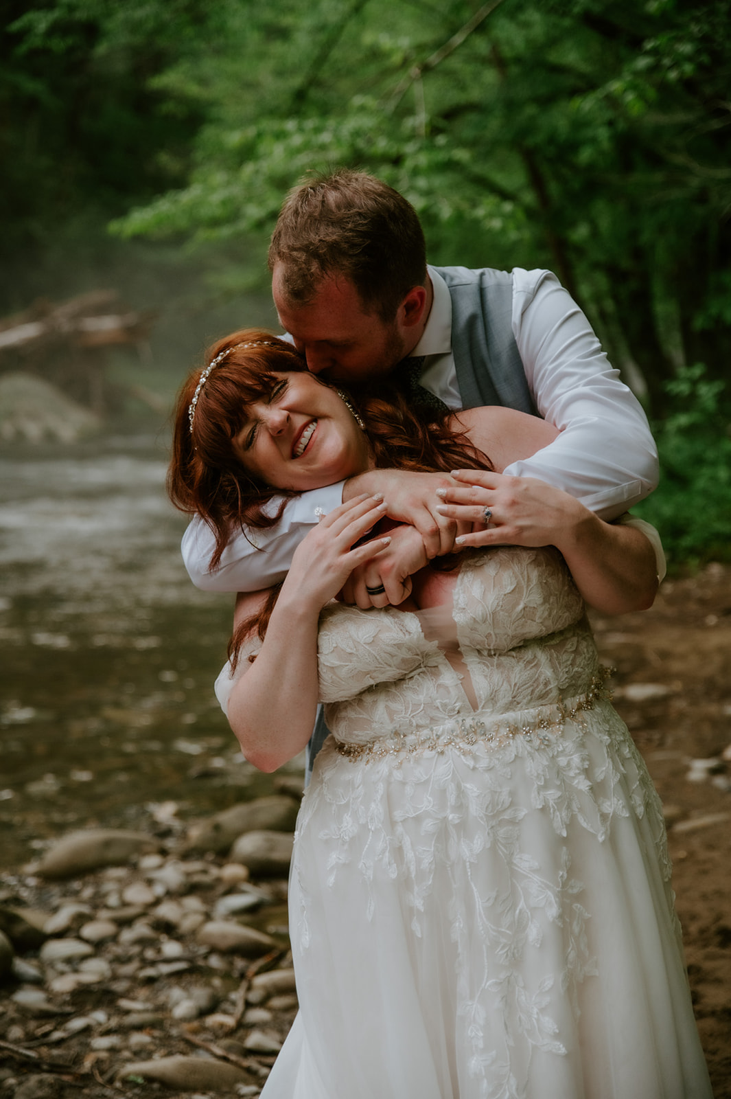 Groom embracing the bride from behind in a forest clearing during intimate elopement portraits.