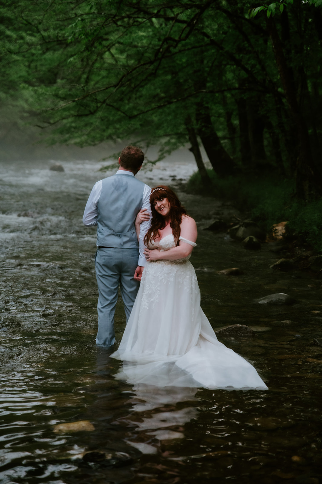Bride and groom standing barefoot in a foggy river during an adventurous elopement portrait