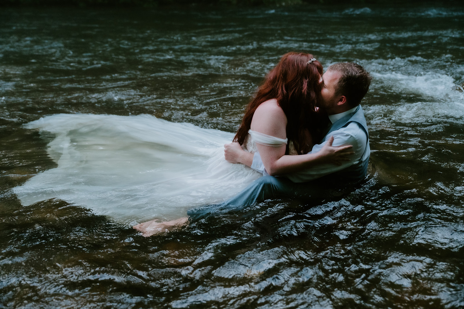 Bride and groom kissing in the river, holding each other tightly during their Smoky Mountain elopement adventure.