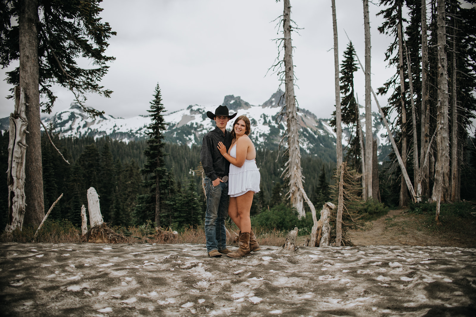 Wide landscape image of a couple celebrating together beside a reflective mountain lake during a Washington elopement.