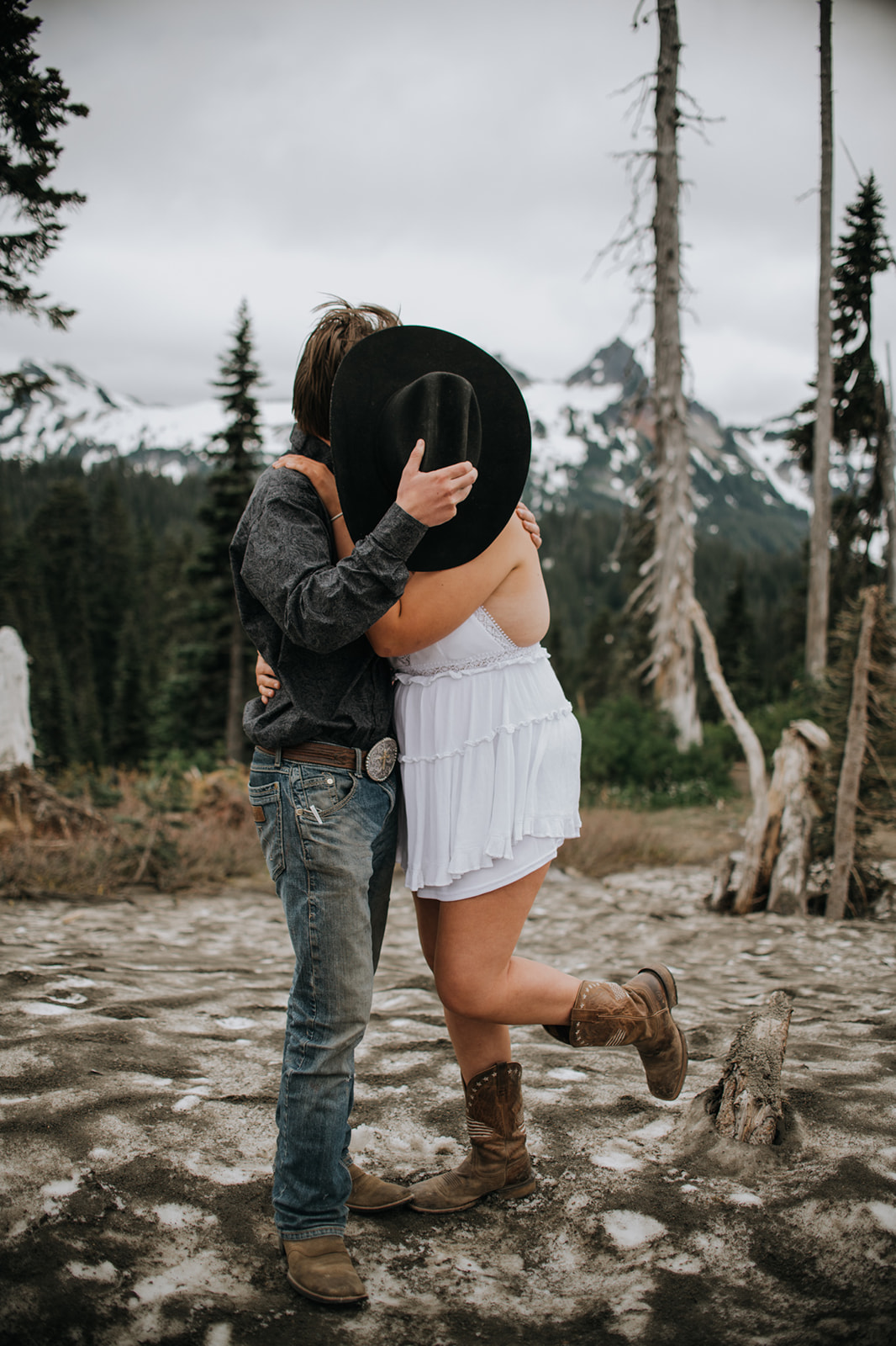 Couple embracing on a rocky overlook with mountain views while they elope in Washington, wearing casual elopement attire in an alpine landscape.