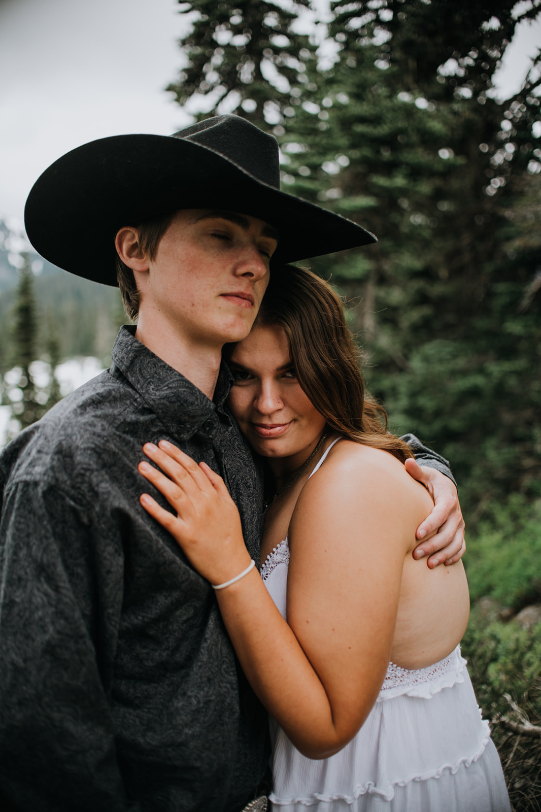 Couple wrapped in each other’s arms in a forest clearing while they elope in Washington, dressed in casual, adventure-ready outfits.