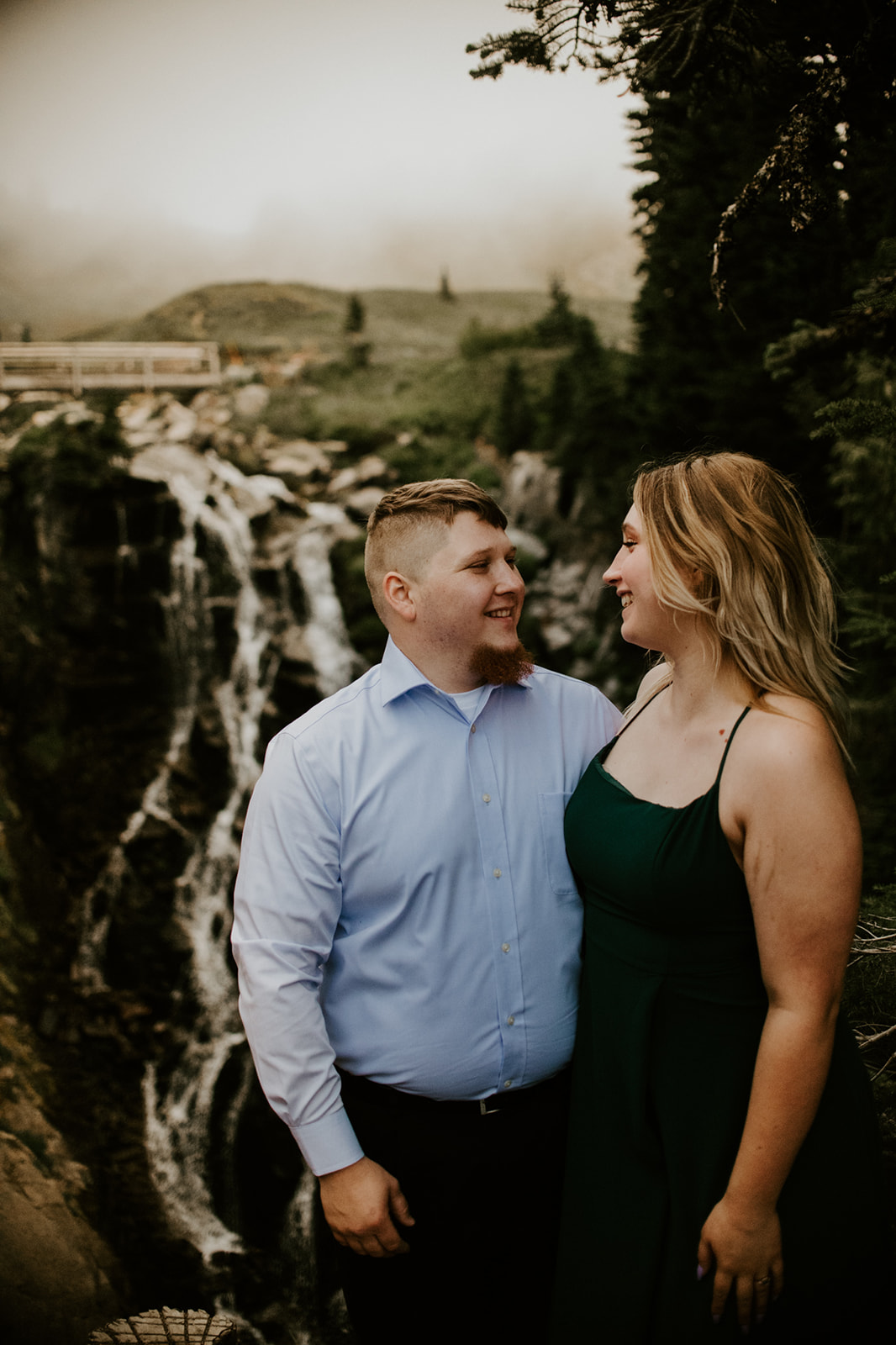 Couple standing close together near a waterfall overlook during a misty Washington elopement adventure.