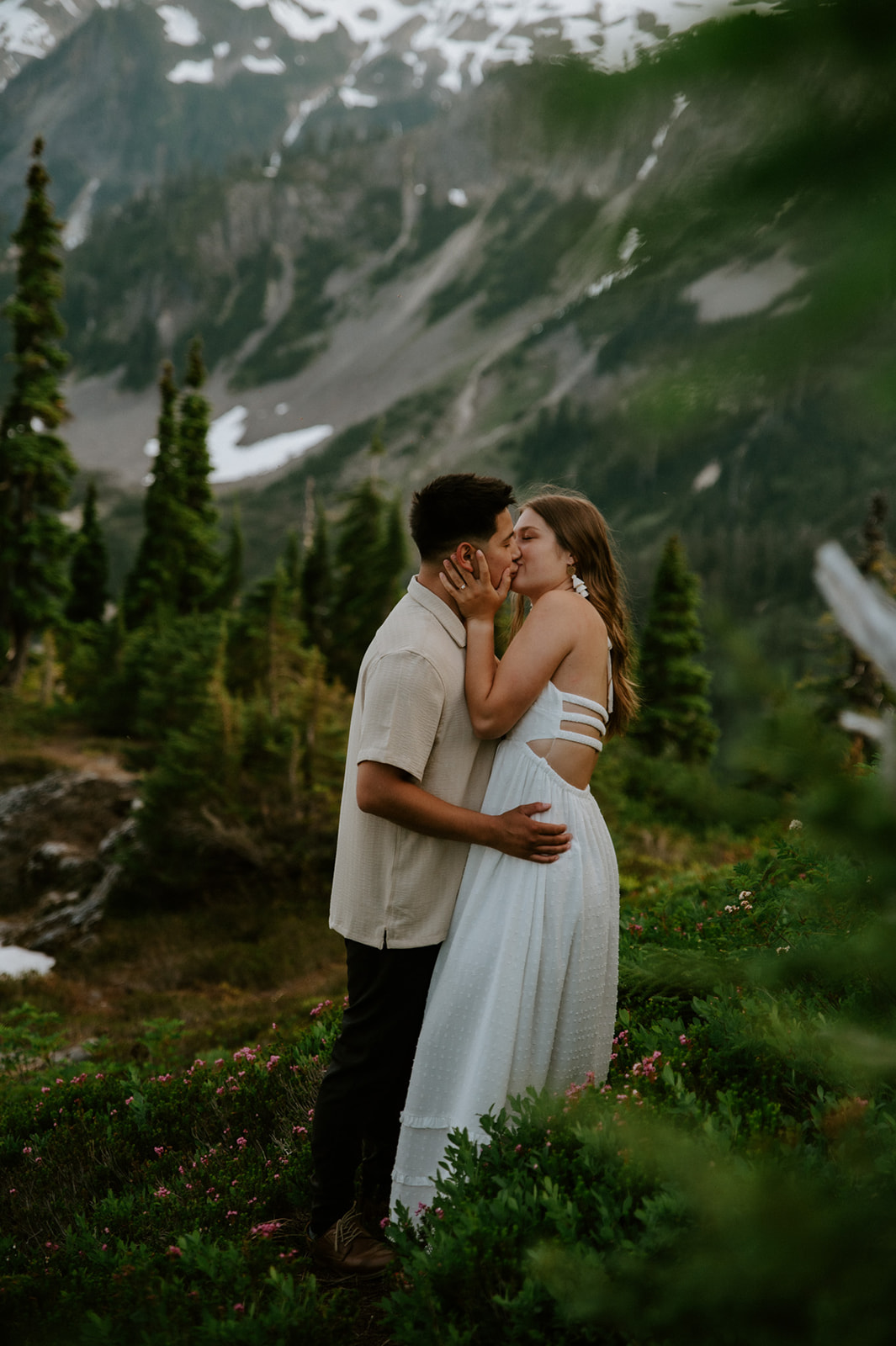 Intimate embrace on rocky overlook with glacier peaks behind them at North Cascades elopement location