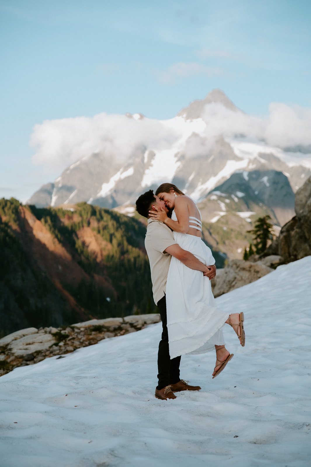 North Cascades elopement couple embracing on a snowy slope with dramatic mountain backdrop