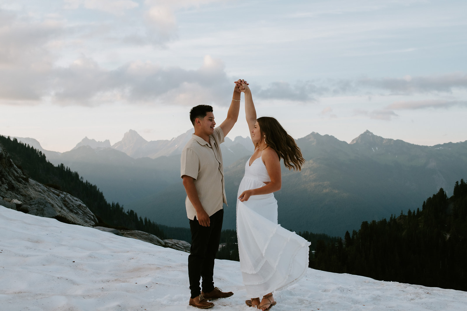 Couple dancing together on snow at high elevation with mountain skyline views during their north cascades elopement