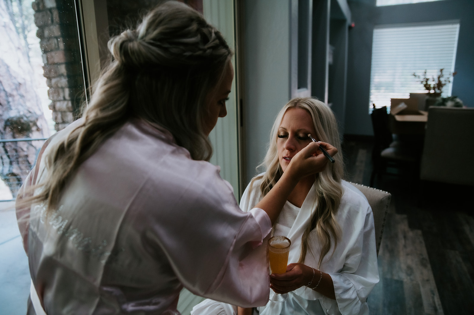 Bride getting ready in a cabin while sipping a drink before heading into the woods to elope in Arizona.
