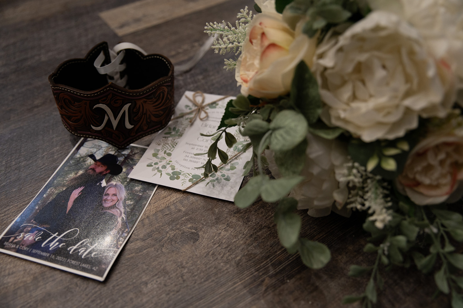 Wedding details including bouquet, invitation suite, leather cuff, and save-the-date card for a couple planning to elope in Arizona.