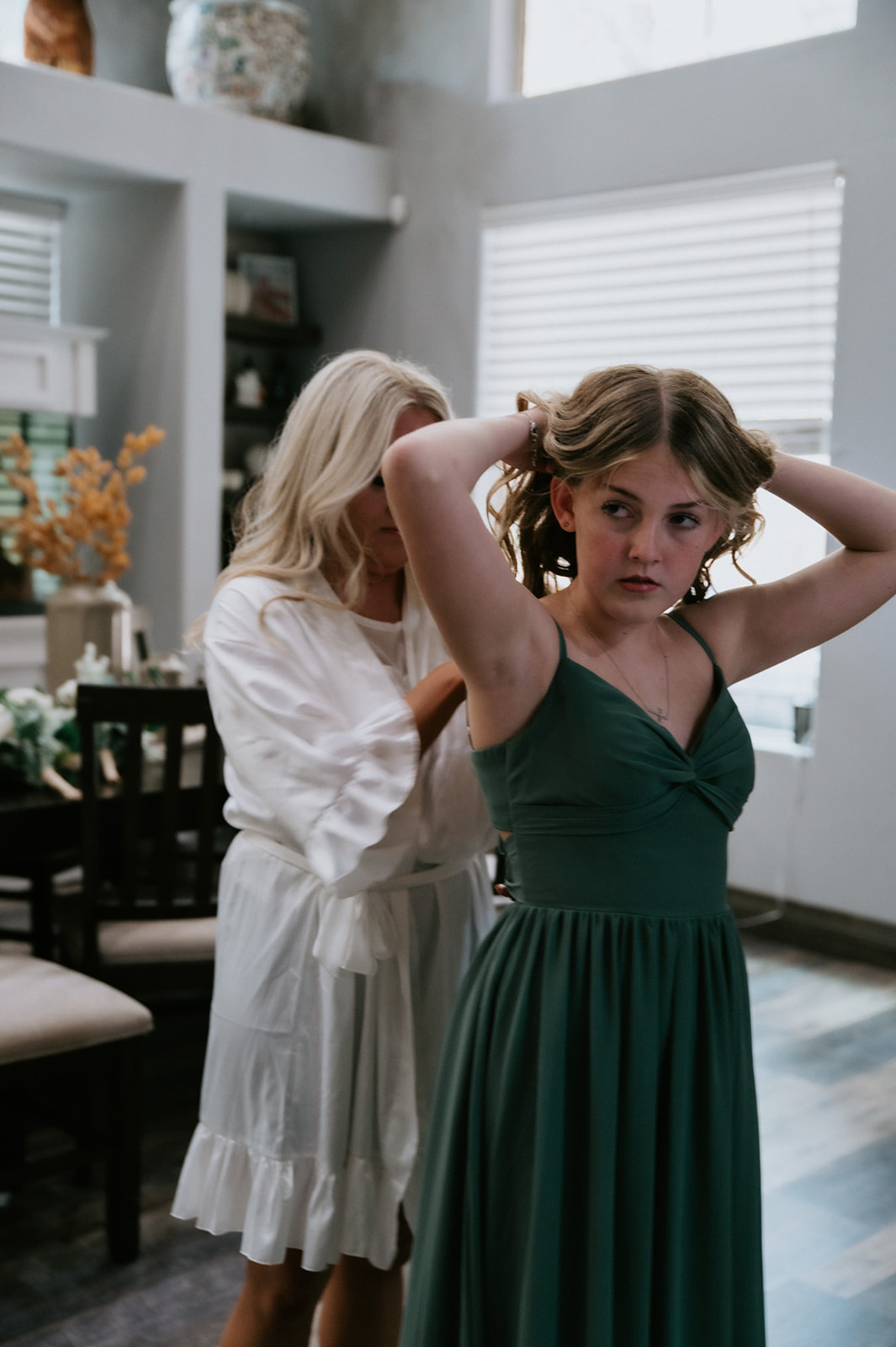 Bride helping a young bridesmaid get ready inside a cozy cabin before her forest elopement.