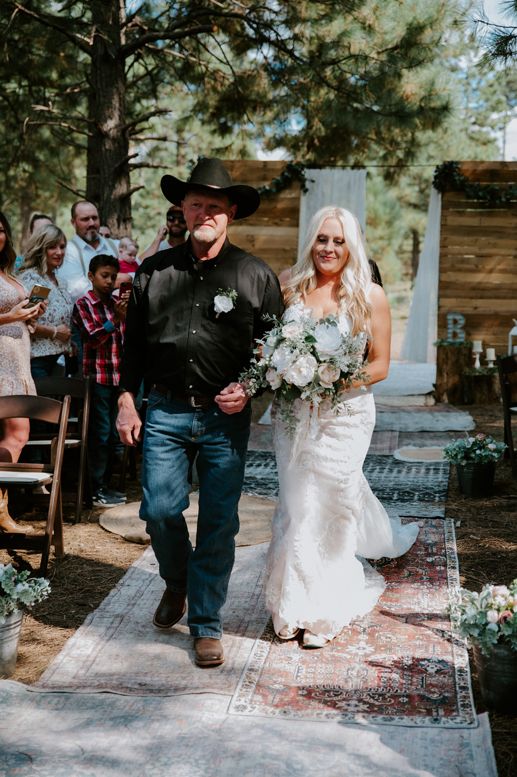 Bride walking down a forest aisle with her father during an intimate outdoor wedding in Arizona.