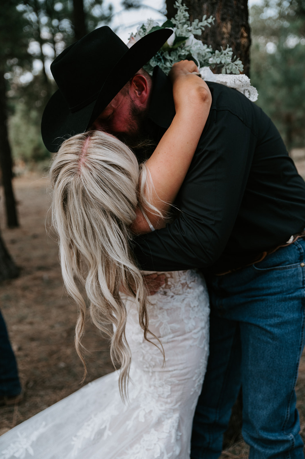 Close-up of bride and groom embracing tightly in a quiet pine forest moments after they elope in Arizona.