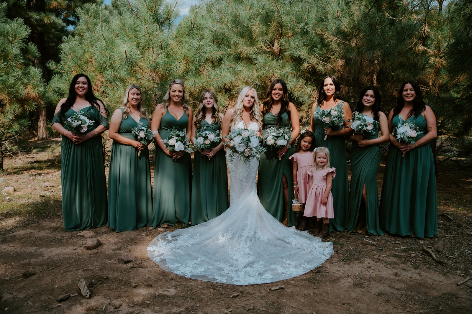 Bride surrounded by bridesmaids in deep green dresses during an Arizona forest elopement.