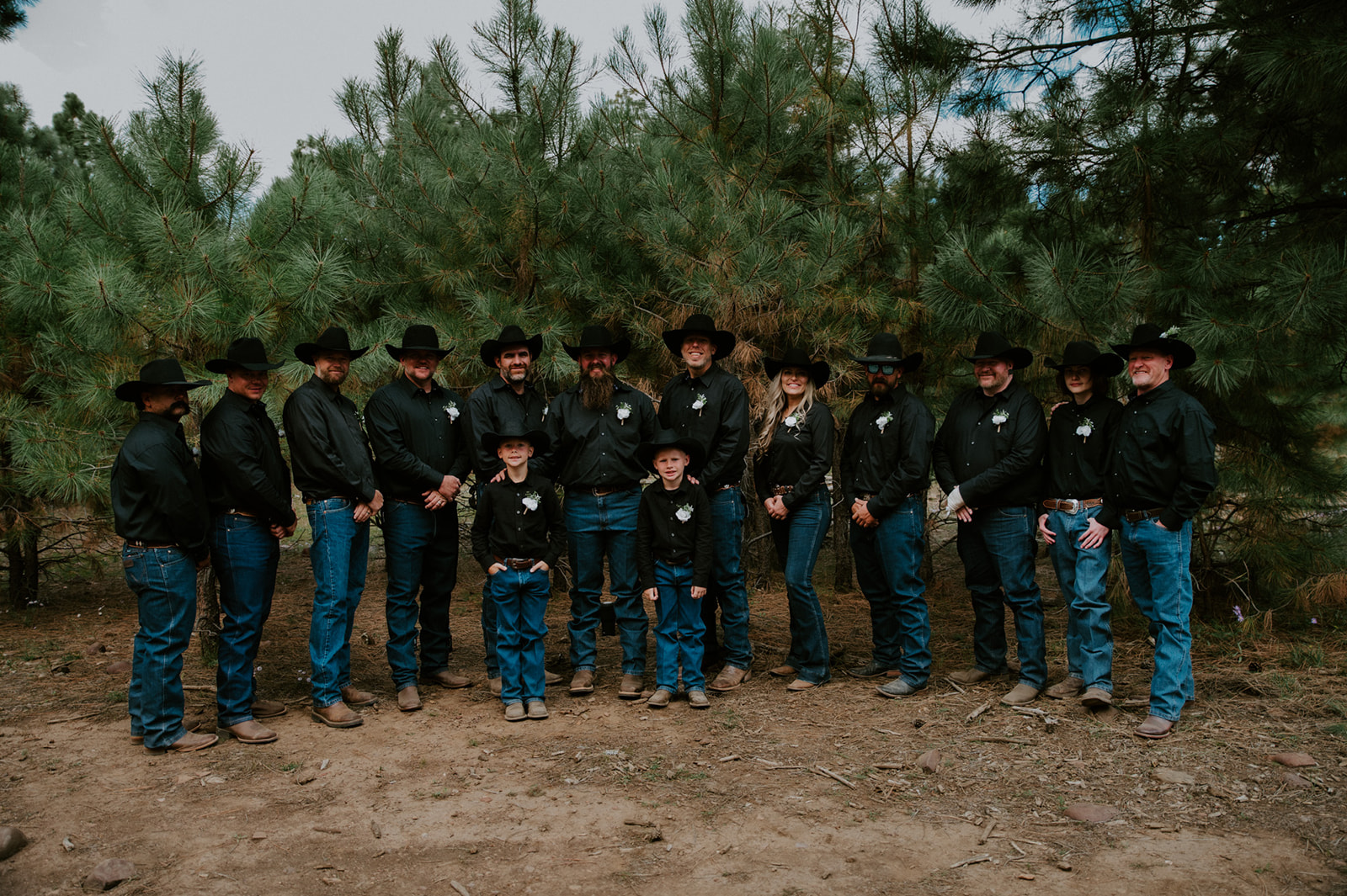 Groom and groomsmen in black cowboy hats posing together in the woods before they elope in Arizona.